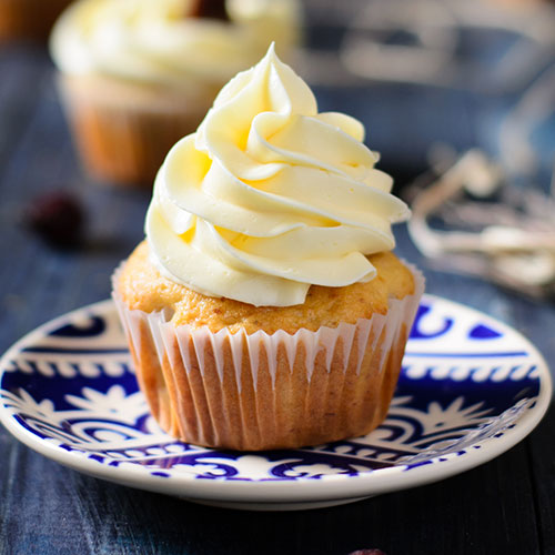 A banana cupcake with beautiful white frosting.